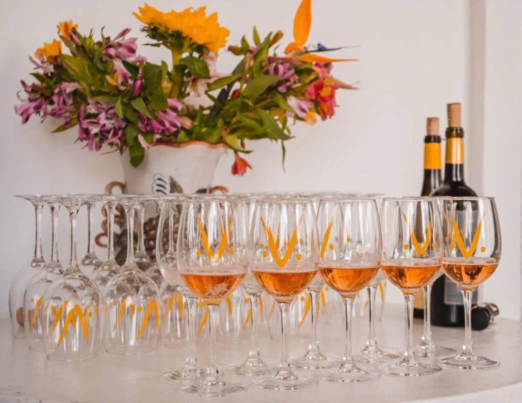 Copas con vino anaranjado frente a un florero